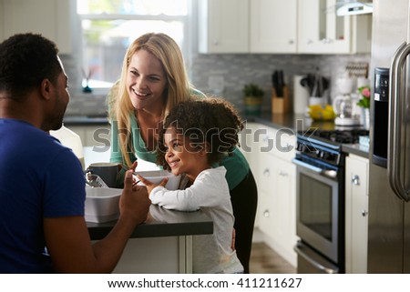 Mixed race couple and daughter talk together in the kitchen
