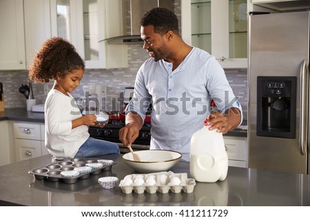 Black dad and young daughter baking together in the kitchen