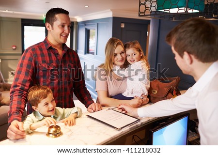 Family Checking In At Hotel Reception Desk