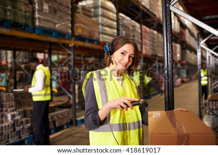 Woman using a barcode reader in a warehouse looks to camera