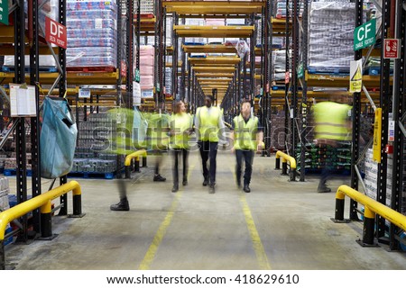 Staff in reflective vests walking to camera in a warehouse