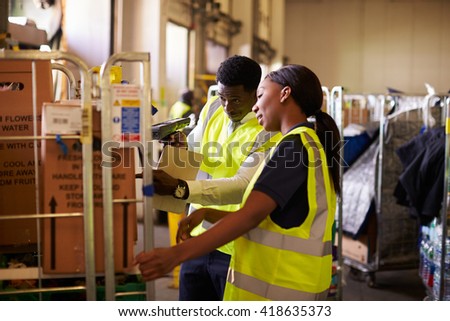 Woman prepares roll cage for delivery, checked by supervisor