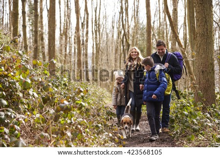 Family with pet dog walk through a wood, boy turning round