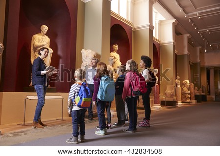 Pupils And Teacher On School Field Trip To Museum With Guide