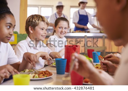 Primary school kids at a table in school cafeteria, close up