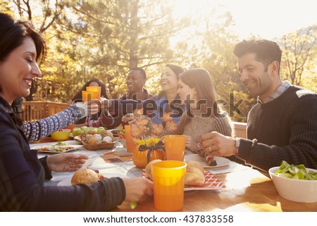 Group of happy friends eat and drink at a table at a barbecue