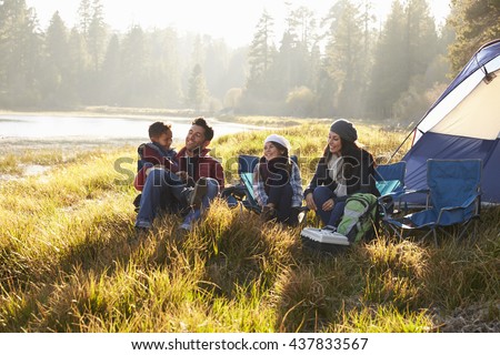 Happy family on a camping trip relaxing by their tent