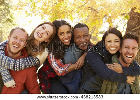 Portrait of friends piggybacking during a hike in a forest