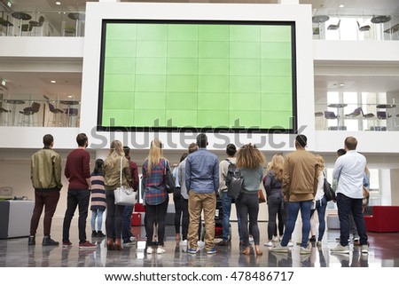 Students looking up at a big screen in university building