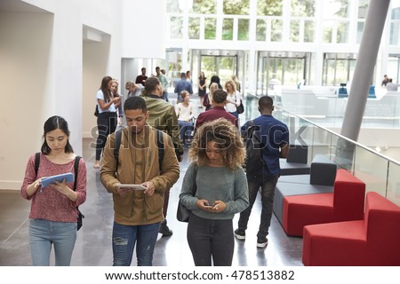 Students walk in university campus using tablets and phone