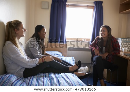 Female Students Relaxing In Bedroom Of Campus Accommodation