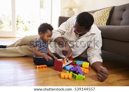 Grandfather And Grandson Playing With Toys On Floor At Home