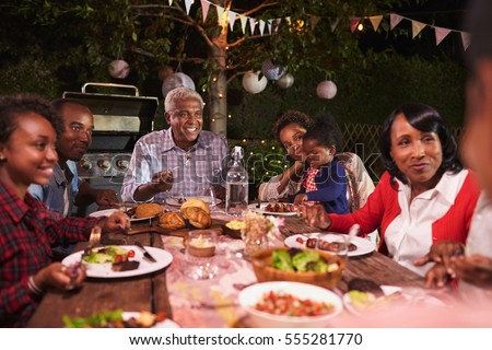 Multi generation family eating dinner in garden, close up