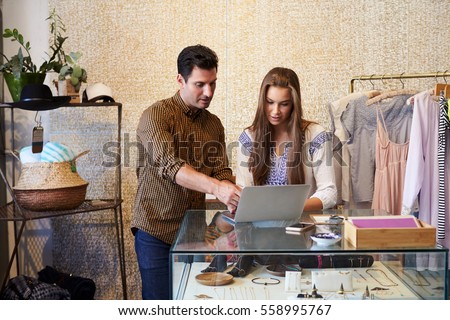 Man and young woman working together in clothes shop