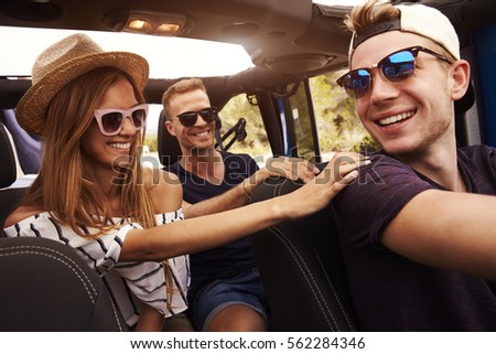 Group Of Friends Driving Open Top Car On Country Road