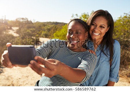 Mother And Adult Daughter Taking Selfie With Phone On Walk
