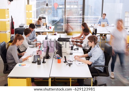 Staff walking through a busy open plan office, side view