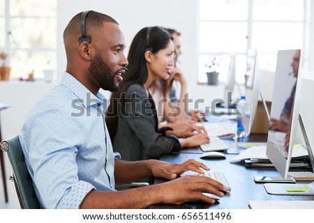 Young black man with headset working at computer in office