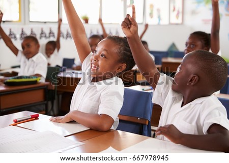 Kids raising hands during elementary school lesson, close up