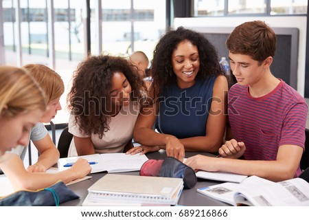 Teacher studying school books in class with high school kids