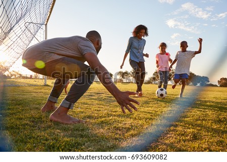 A boy kicks a football during a game with his family