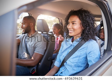 Young black family with children in a car going on road trip