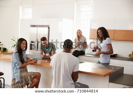 Friends Talking And Drinking Coffee In Modern Kitchen