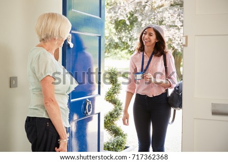Senior woman opens door to female care worker showing her ID