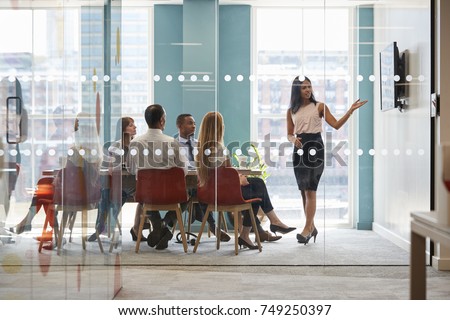 Female boss shows presentation on screen at business meeting