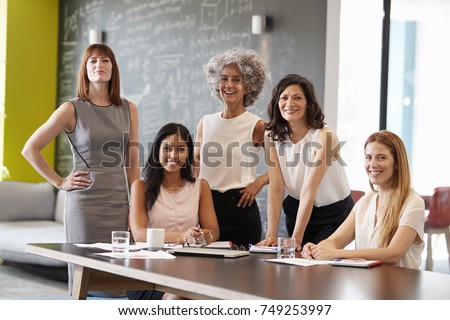 Five female colleagues at a work meeting smiling to camera
