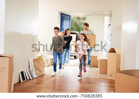 Family Carrying Boxes Into New Home On Moving Day