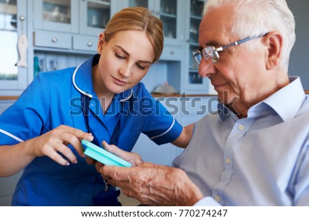 Nurse Helping Senior Man To Organize Medication On Home Visit