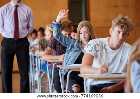 Teenage Student Sitting Examination Asking Teacher Question