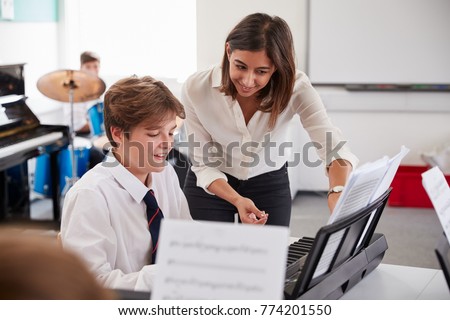 Male Pupil With Teacher Playing Piano In Music Lesson