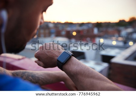 Male urban runner checks fitness app on smartwatch, close up