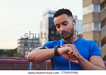 Male runner uses app on smartwatch in urban street, close up