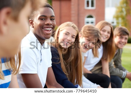 Group Of Teenage Students Sitting Outside School Buildings