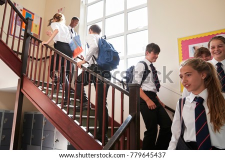 Group Of Teenage Students In Uniform Walking Between Classrooms