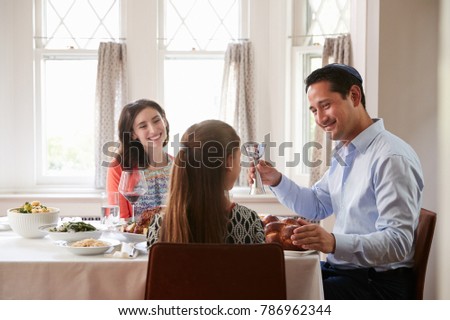 Jewish man holding kiddish cup blesses his family at Shabbat