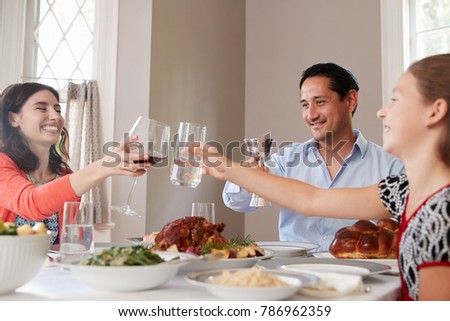 Jewish family raising glasses at the table for Shabbat meal