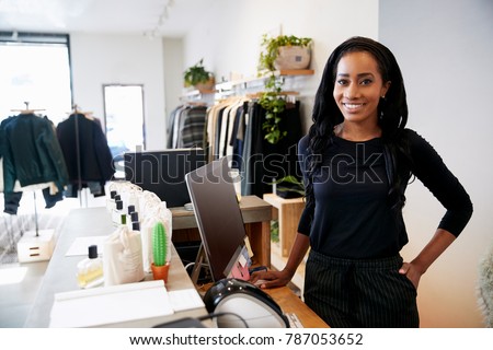 Female assistant smiling behind the counter in clothes store