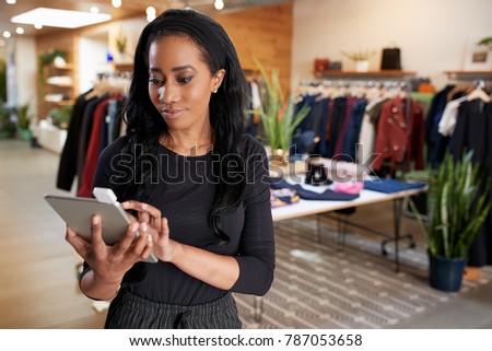 Young black woman using tablet computer in a clothes shop