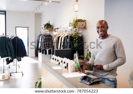 Male assistant smiling behind the counter in clothing store
