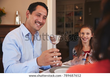 Jewish man holding kiddish cup blesses family at Shabbat