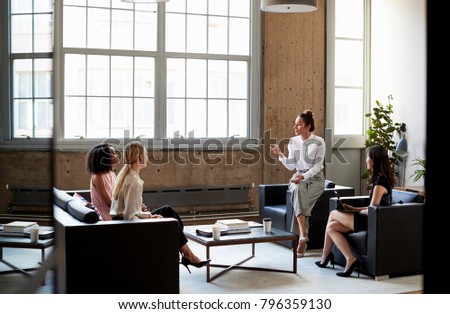 Seated female manager talking to team at an informal meeting