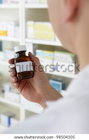Pharmacist holding prescription pill bottle