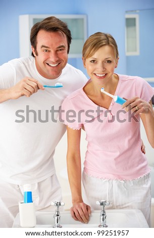Couple cleaning teeth together in bathroom