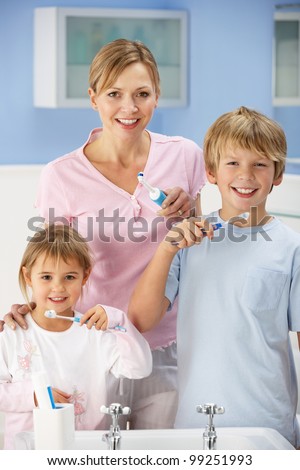 Mother and children cleaning teeth in bathroom