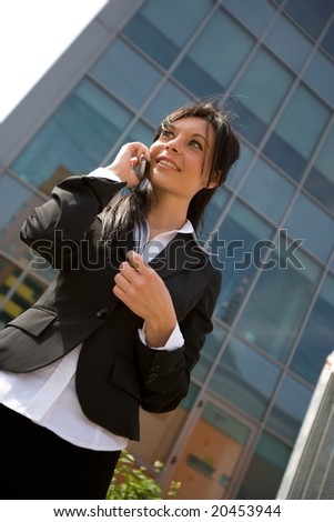 young businesswoman making a phone call in front of an office building