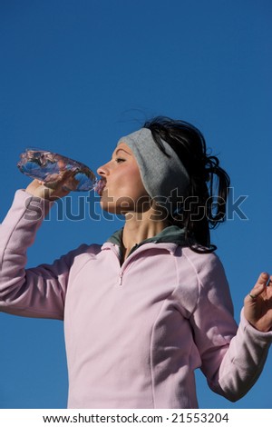 woman drinks water from a bottle outdoors